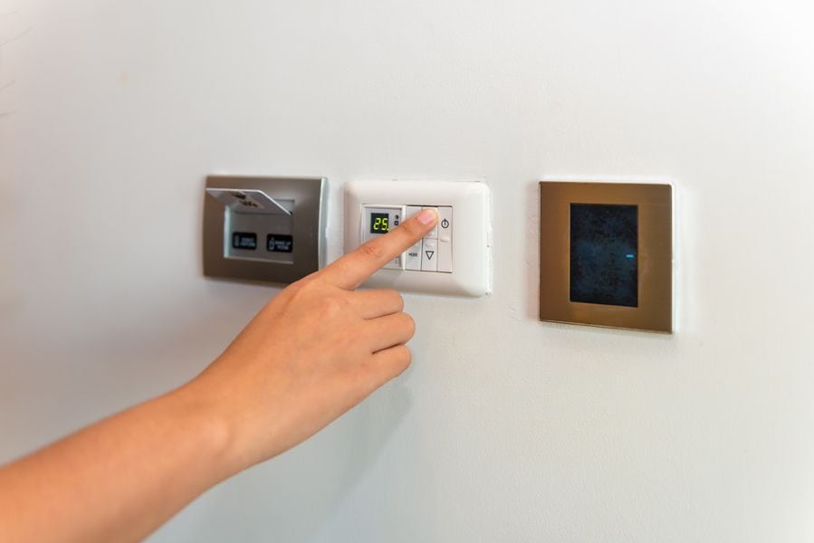 Image of someone pressing on a control panel attached to HVAC systems. Heat Pump Versus Furnace.