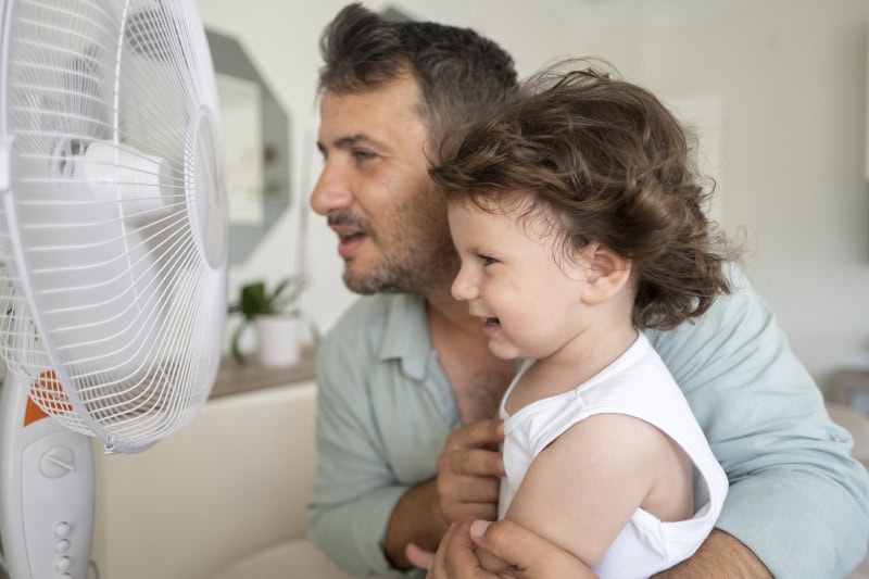 Dad and daughter in front of a fan.