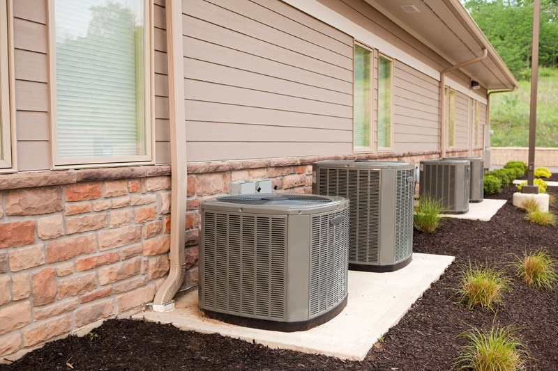 Air conditioner units on slabs at the side of a red brick building