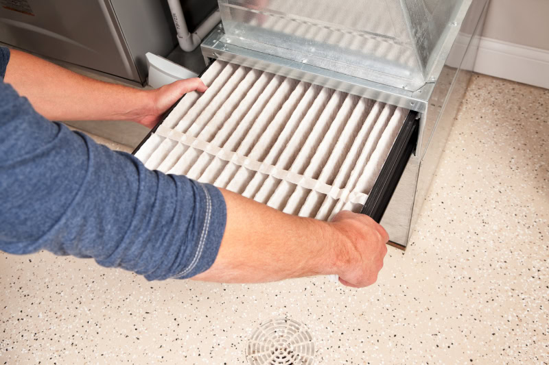A guy changing out the furnace filter.
