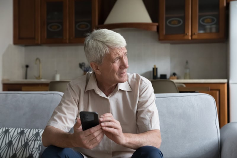 What’s That Smell Coming From My Furnace? Photo of a man looking concerned on his phone, looking out a window.
