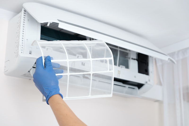 Technician cleaning air conditioner. Hand holding air conditioning filter