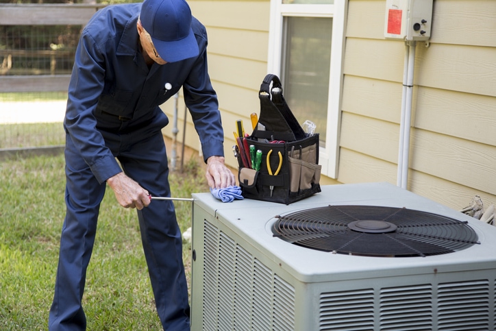 Technician services outside AC units and generator. Senior Adult air conditioner Technician/Electrician services outdoor unit before they hit an equipment shortage