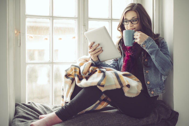 Young woman at home drinking hot tea, wondering why her furnace keeps running.