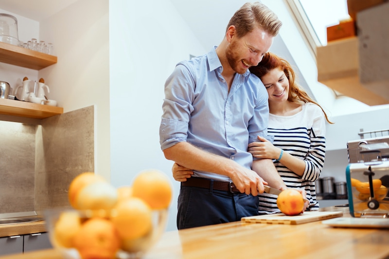 Happy couple making healthy organic orange juice in kitchen