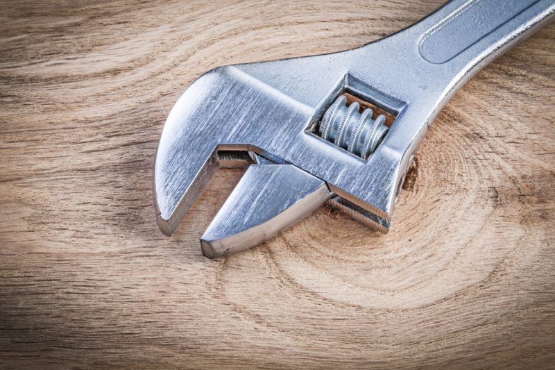 Stainless adjustable spanner on wooden board plumbing concept maintenance