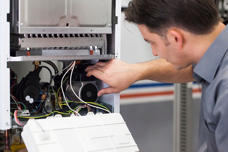 4 Important Heat Pump Maintenance Tips. Man working on repairing a heat pump.