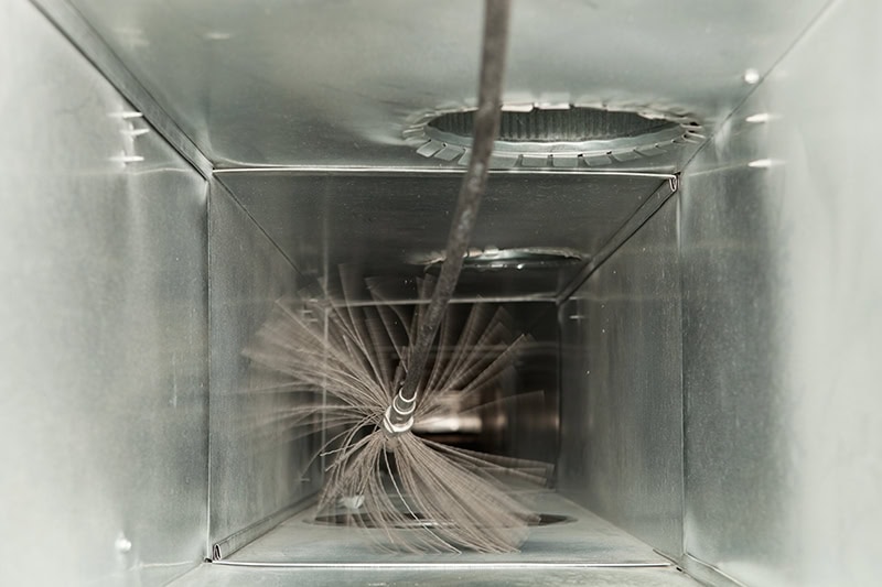 Air vent being cleaned with a brush.