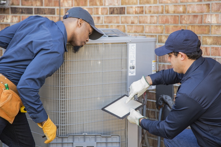 Multi-ethnic team of blue collar air conditioner repairmen at work maintenance.