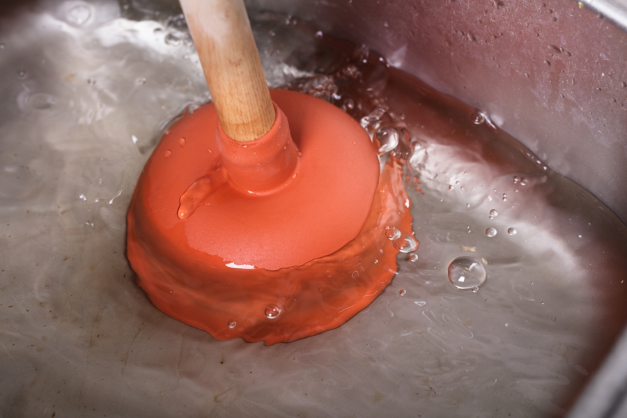 An Orange Cup Plunger In The Washbasin Filled With Water