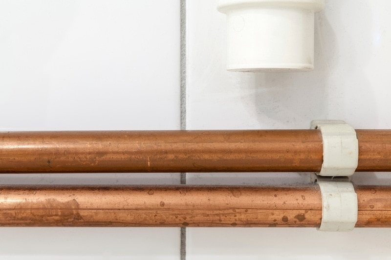 Close up of copper pipes agains a white wall, AC refrigerant leaks