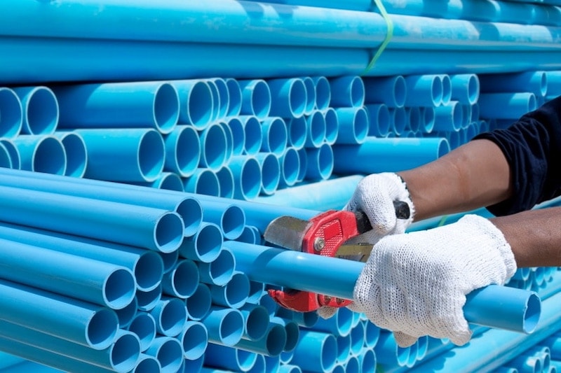 plumbing-material-new-pipes Service technician pulling out new pipes to be cut to size
