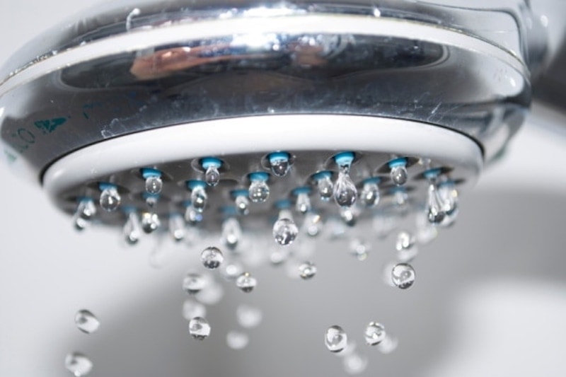 Close up of a shower head dripping, water heater