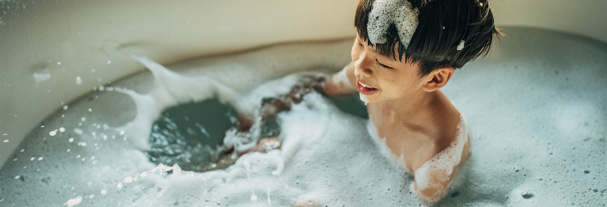 Boy is taking a bath in bathtub.