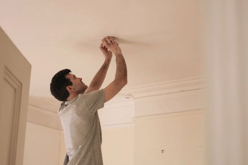 Video - When Do I Need to Replace the Batteries in My Smoke Detector? Image shows man replacing batteries in smoke detector.