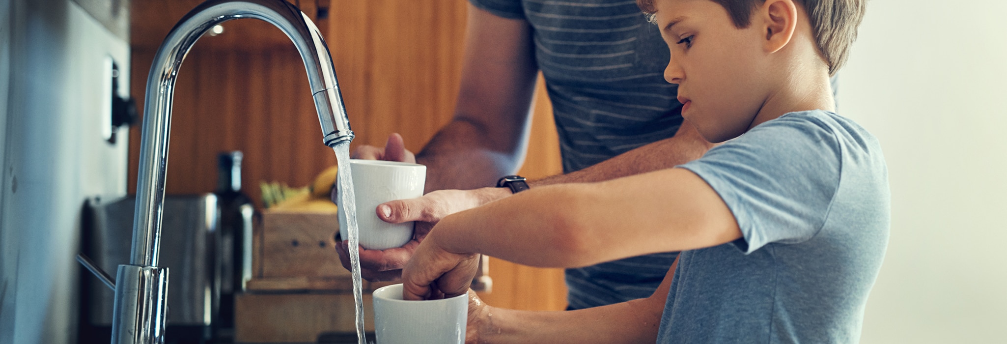 Father and son washing dishes together at home.